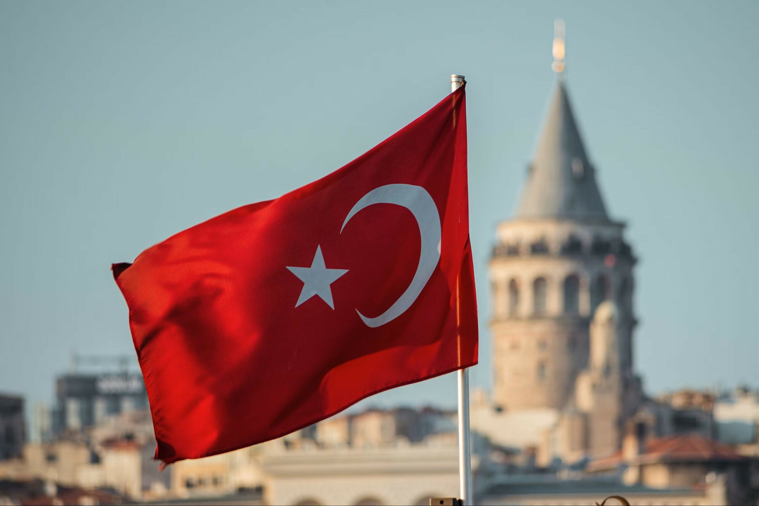 Turkish flag and Galata Tower Istanbul – legal framework for foreign investment Turkish flag flying in front of the Galata Tower in Istanbul at dusk